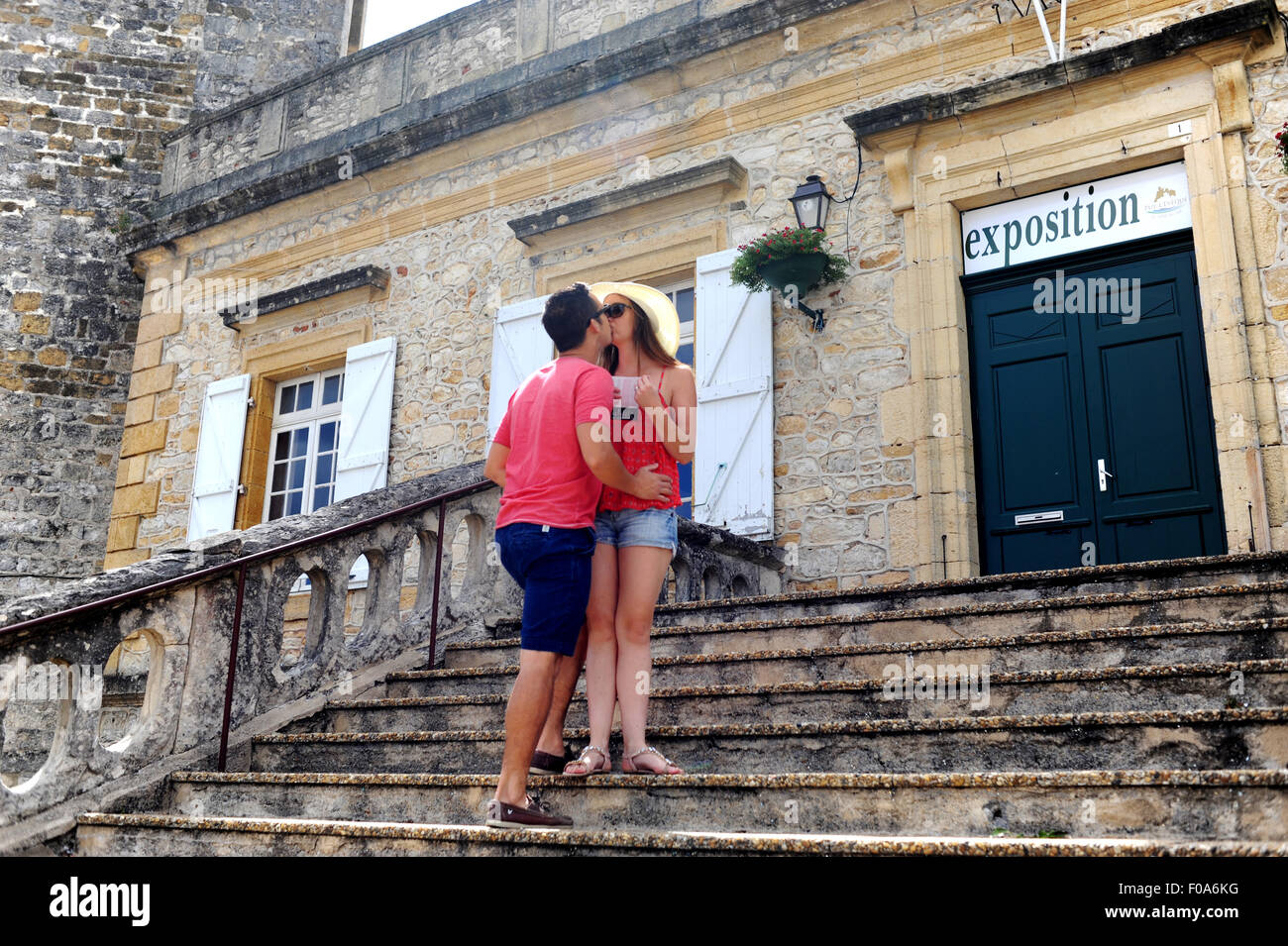 Young couple on holiday kissing on steps of town hall or Marie in Puy-l'Eveque  a small town in Lot Region France Stock Photo