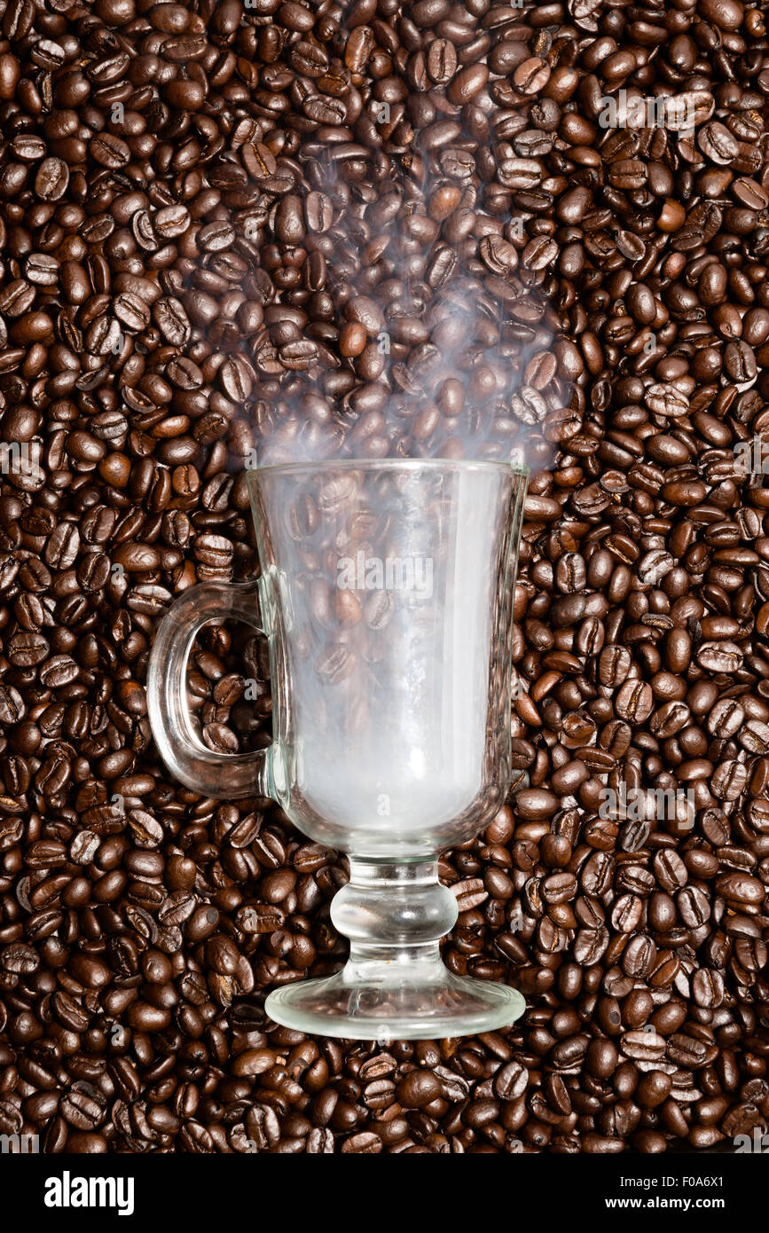 Irish coffee glass stuck in fresh coffee beans. Smoke is coming out of