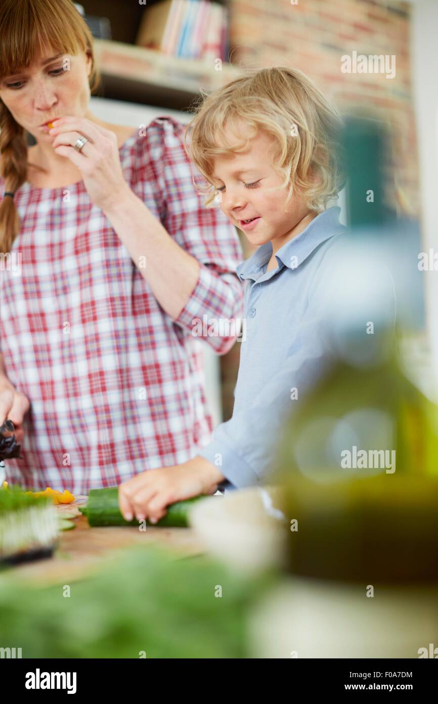 Mother and son slicing cucumber in kitchen Stock Photo