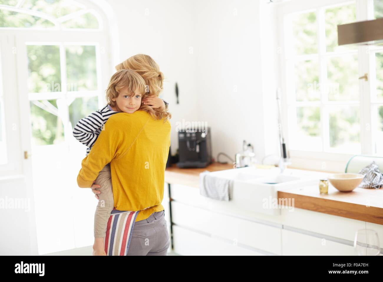 Mother carrying son in kitchen Stock Photo