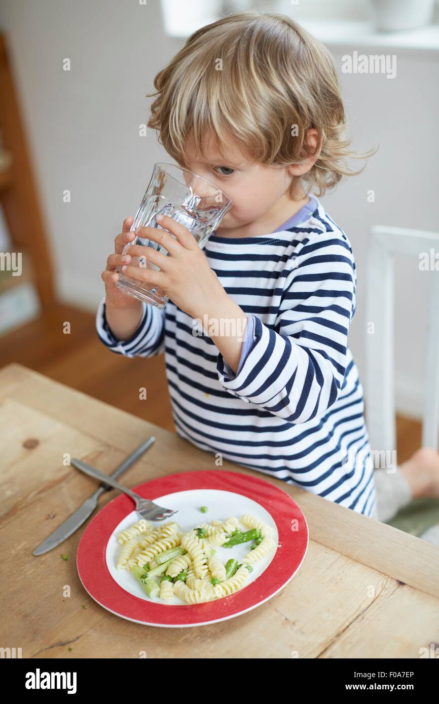 Boy drinking water at dining table Stock Photo