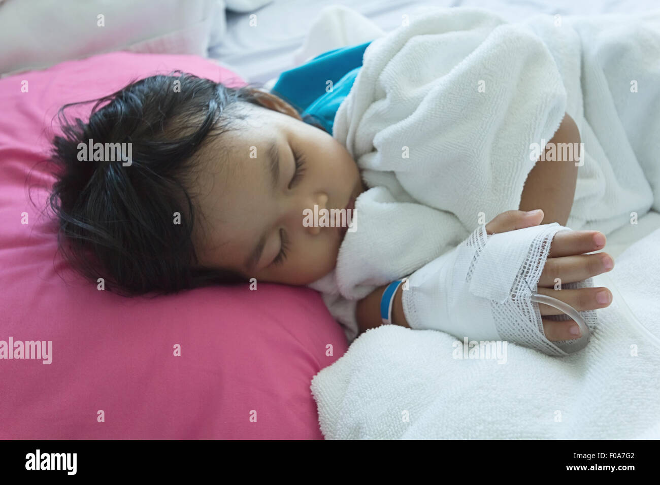 Illness asian kids asleep on a sickbed in hospital, saline intravenous (IV) on hand Stock Photo