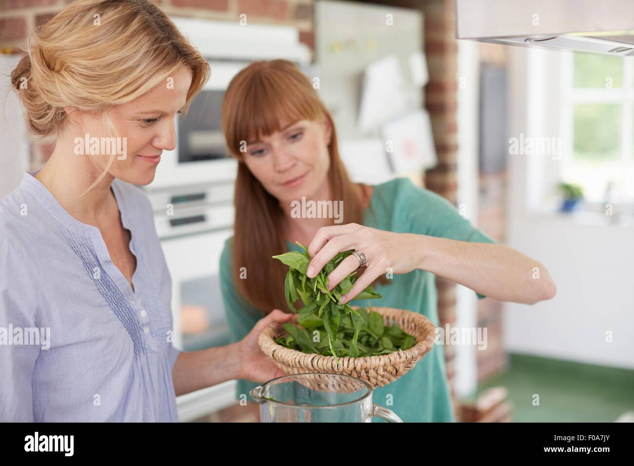 Women preparing green vegan smoothie in kitchen Stock Photo