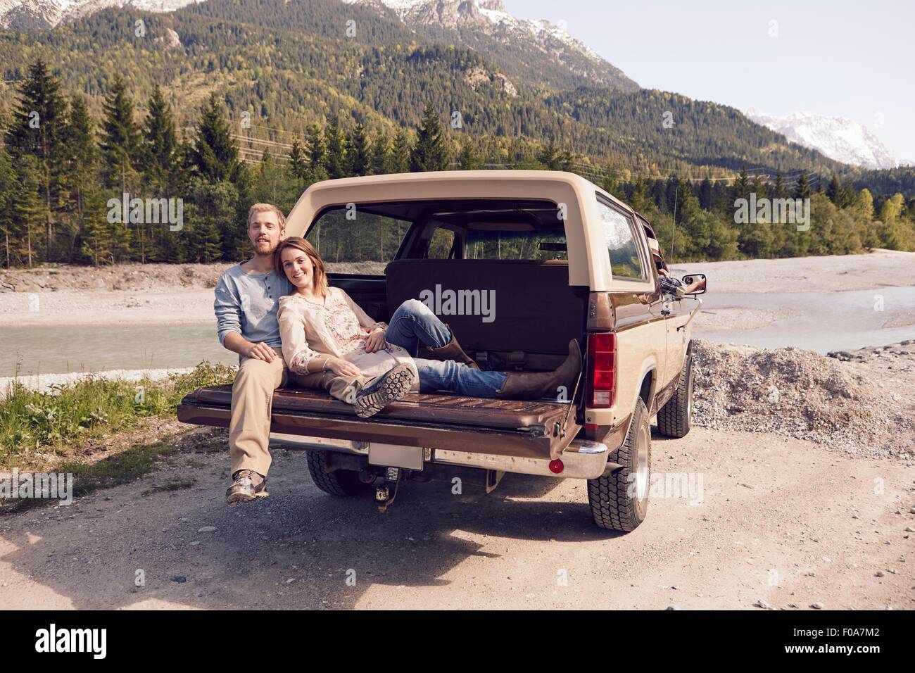 Couple sitting on back of pick up truck, looking at camera, Wallgau, Bavaria, Germany Stock Photo