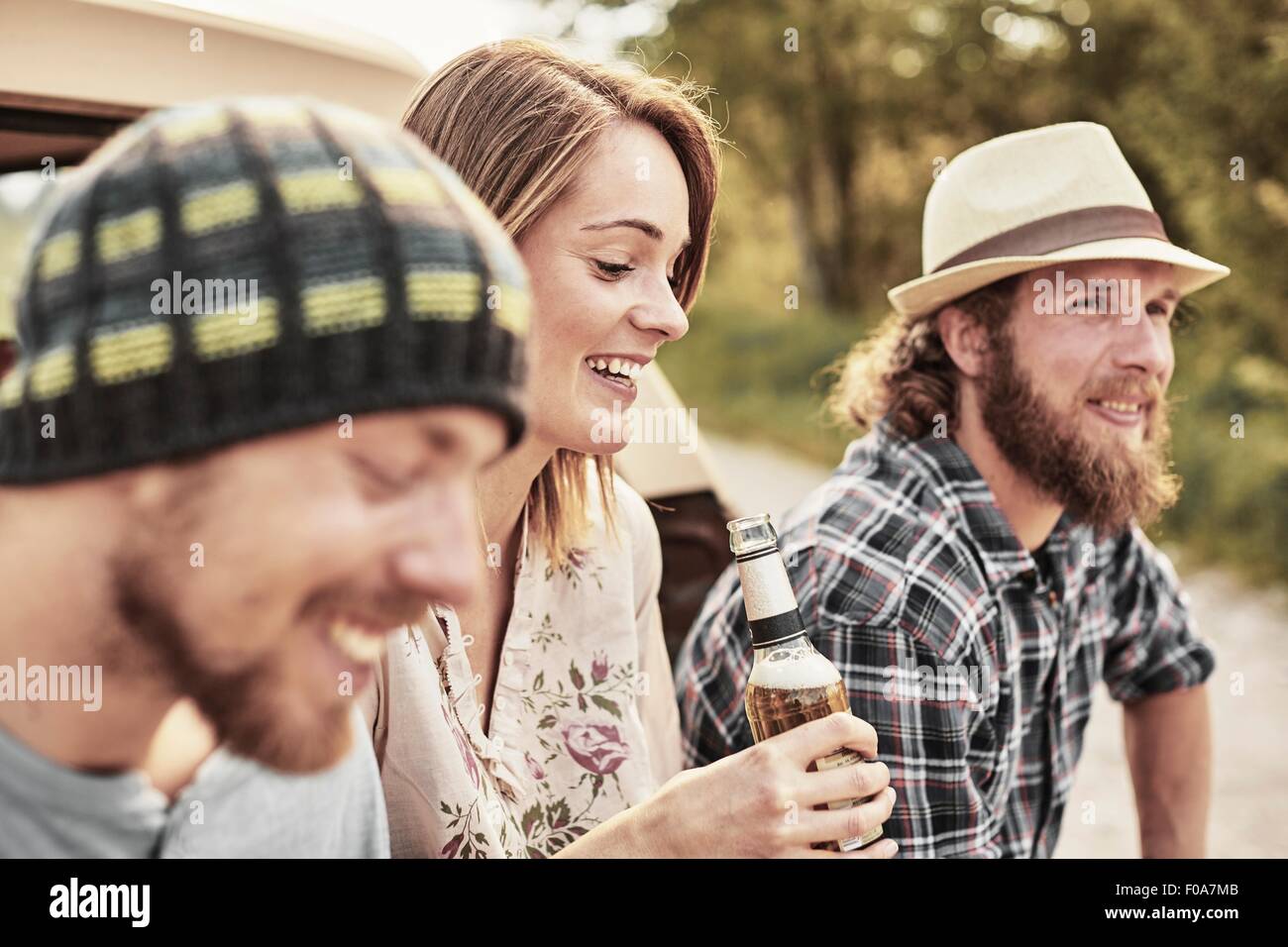 Three people holding bottled beer smiling Stock Photo