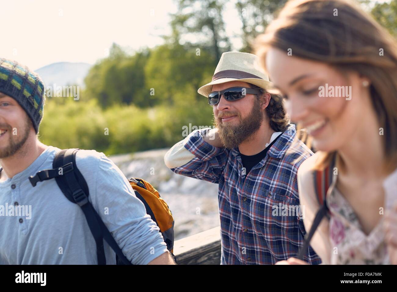 Three people walking together carrying backpacks, smiling Stock Photo