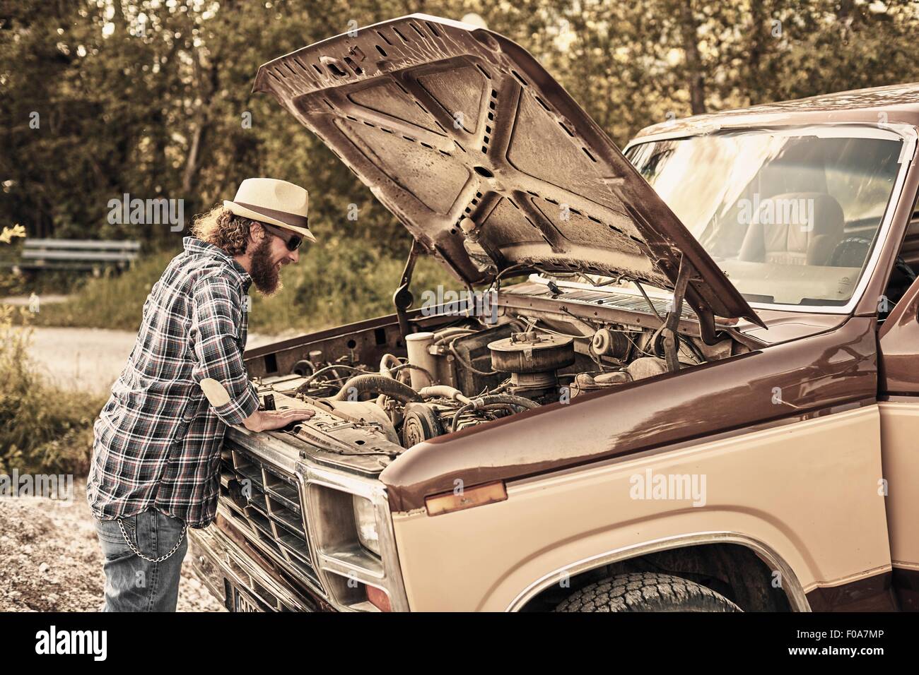 Man looking under open vehicle hood at engine Stock Photo