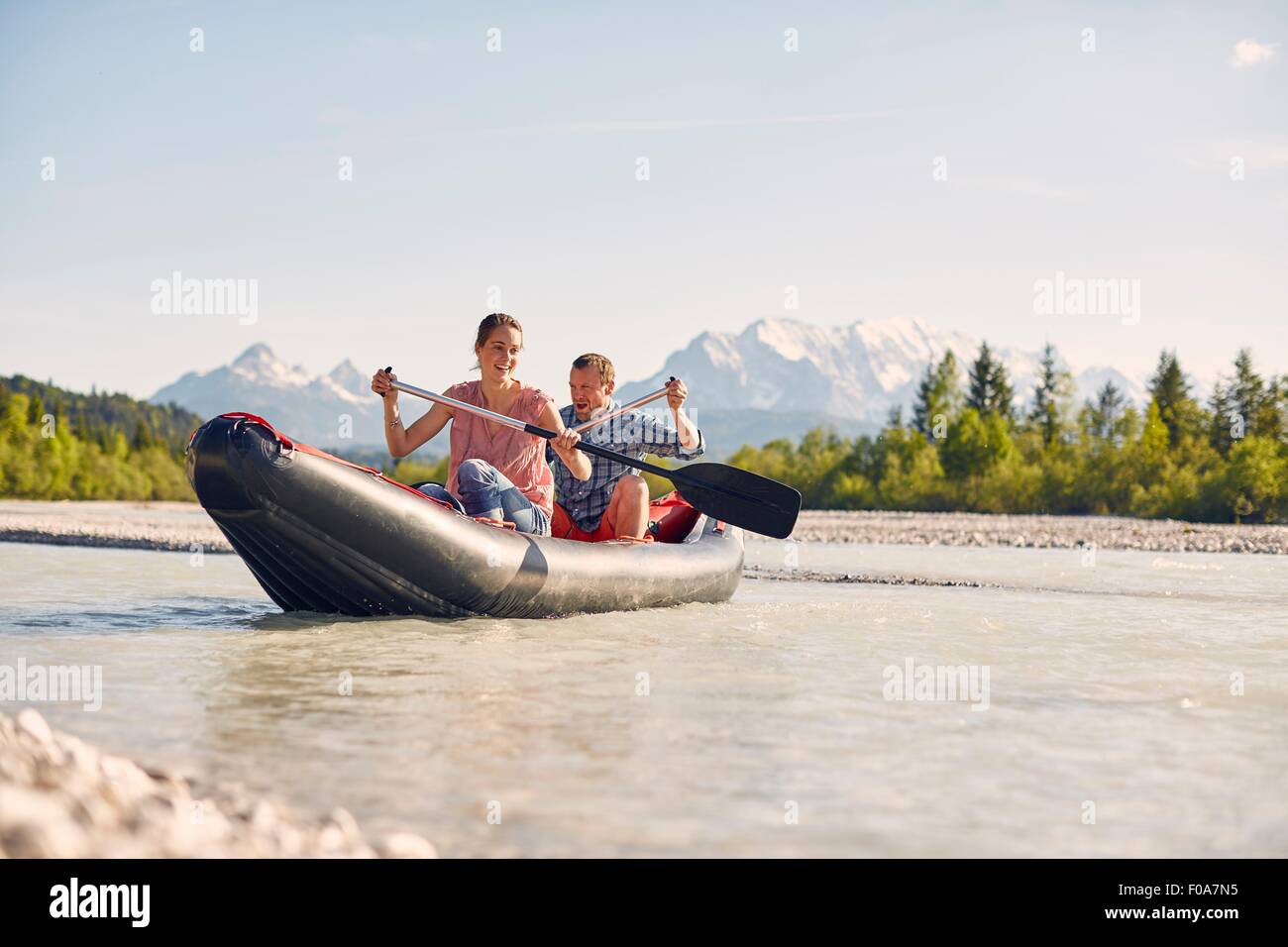 Couple using paddles to steer dinghy on water, Wallgau, Bavaria, germany Stock Photo