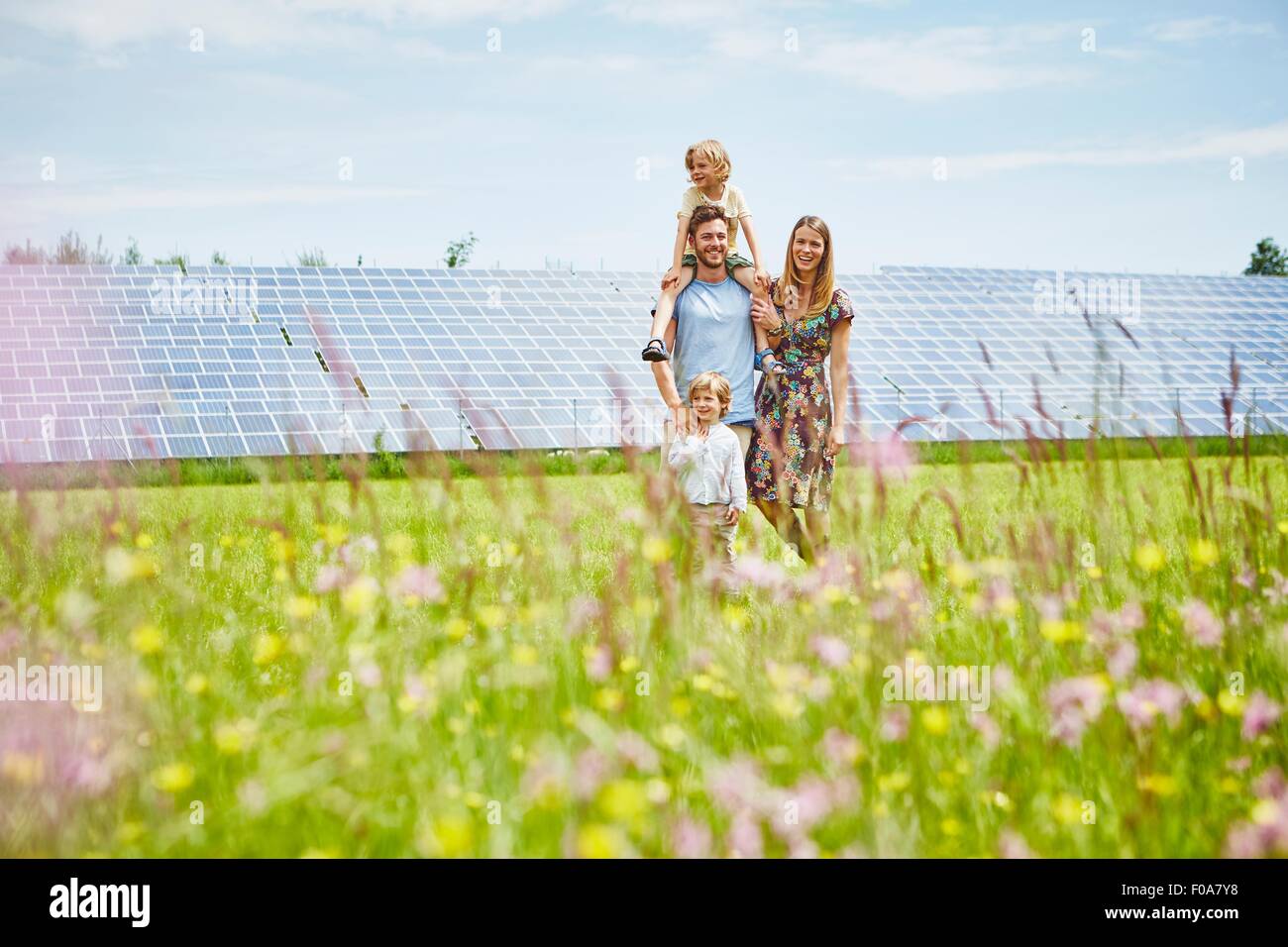 Young family, walking through field next to solar farm Stock Photo