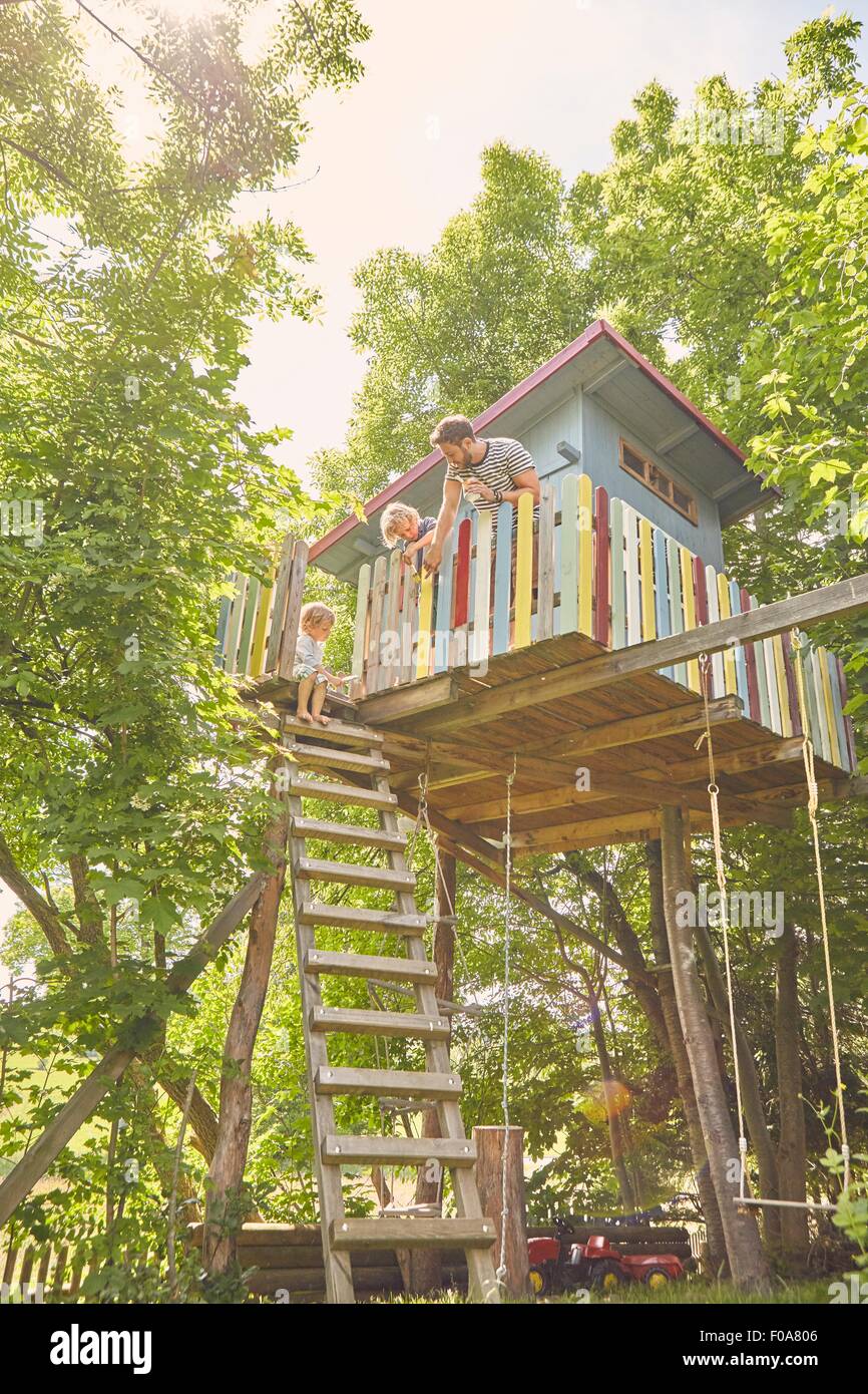 Father and two sons, painting tree house Stock Photo