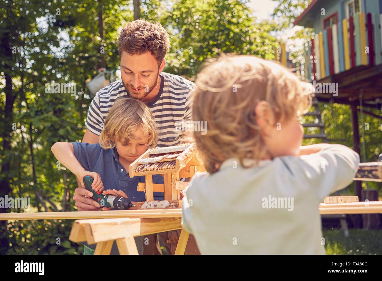 Father and two sons doing woodwork together, outdoors Stock Photo