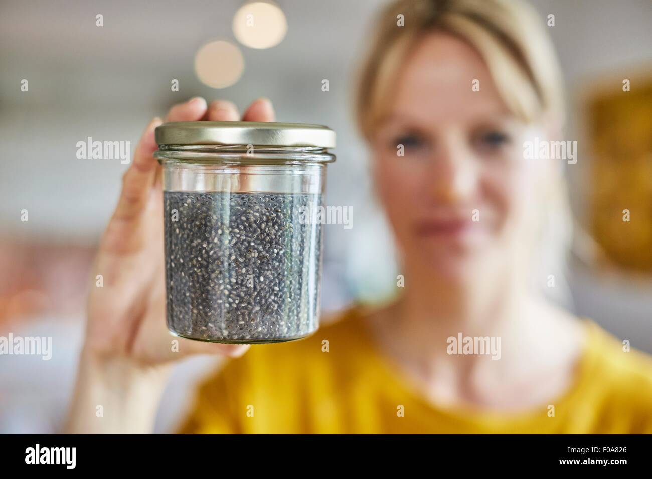 Mature woman holding up jar of seeds, focus on seeds Stock Photo