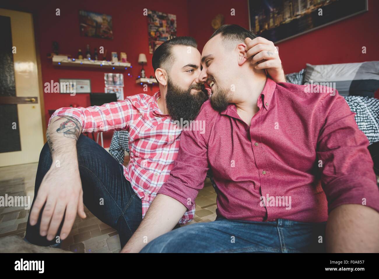 Gay couple rubbing noses in bedroom Stock Photo