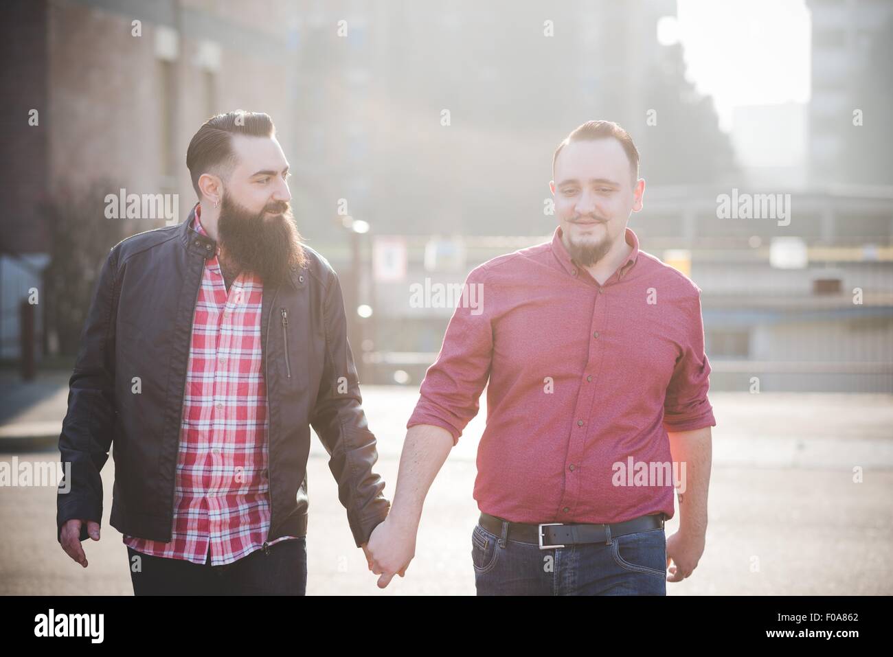 Gay couple walking hand in hand on street Stock Photo