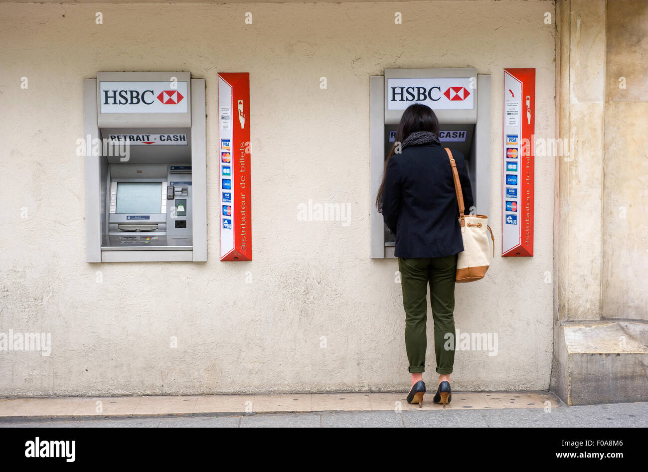 PARIS, FRANCE - JULY 28, 2015: A woman is withdrawing money from an ATM machine on a street in Paris in France. Stock Photo