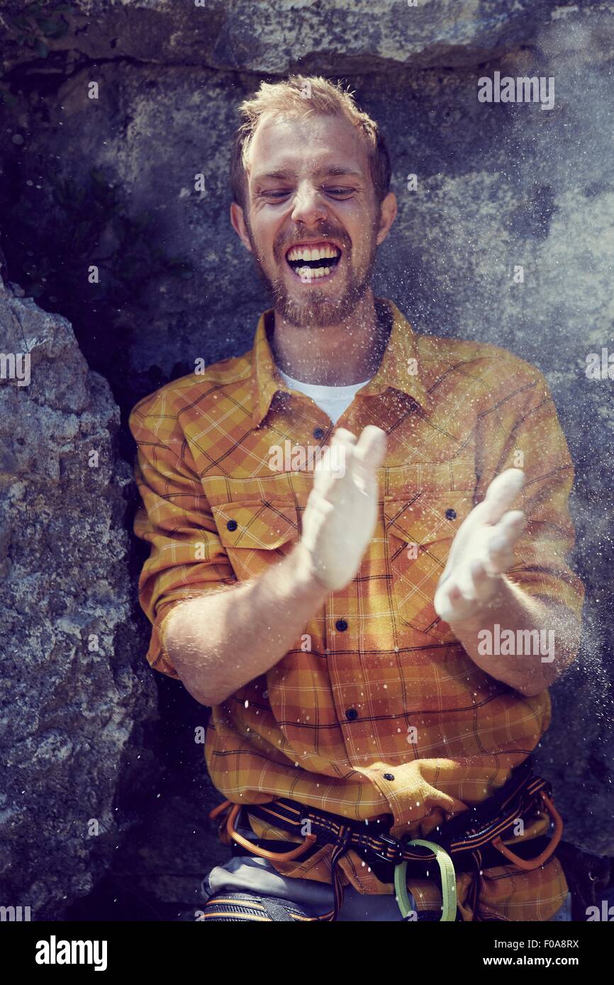 Climber leaning against rock wall clapping chalked hands, Ehrwald, Tyrol, Austria Stock Photo