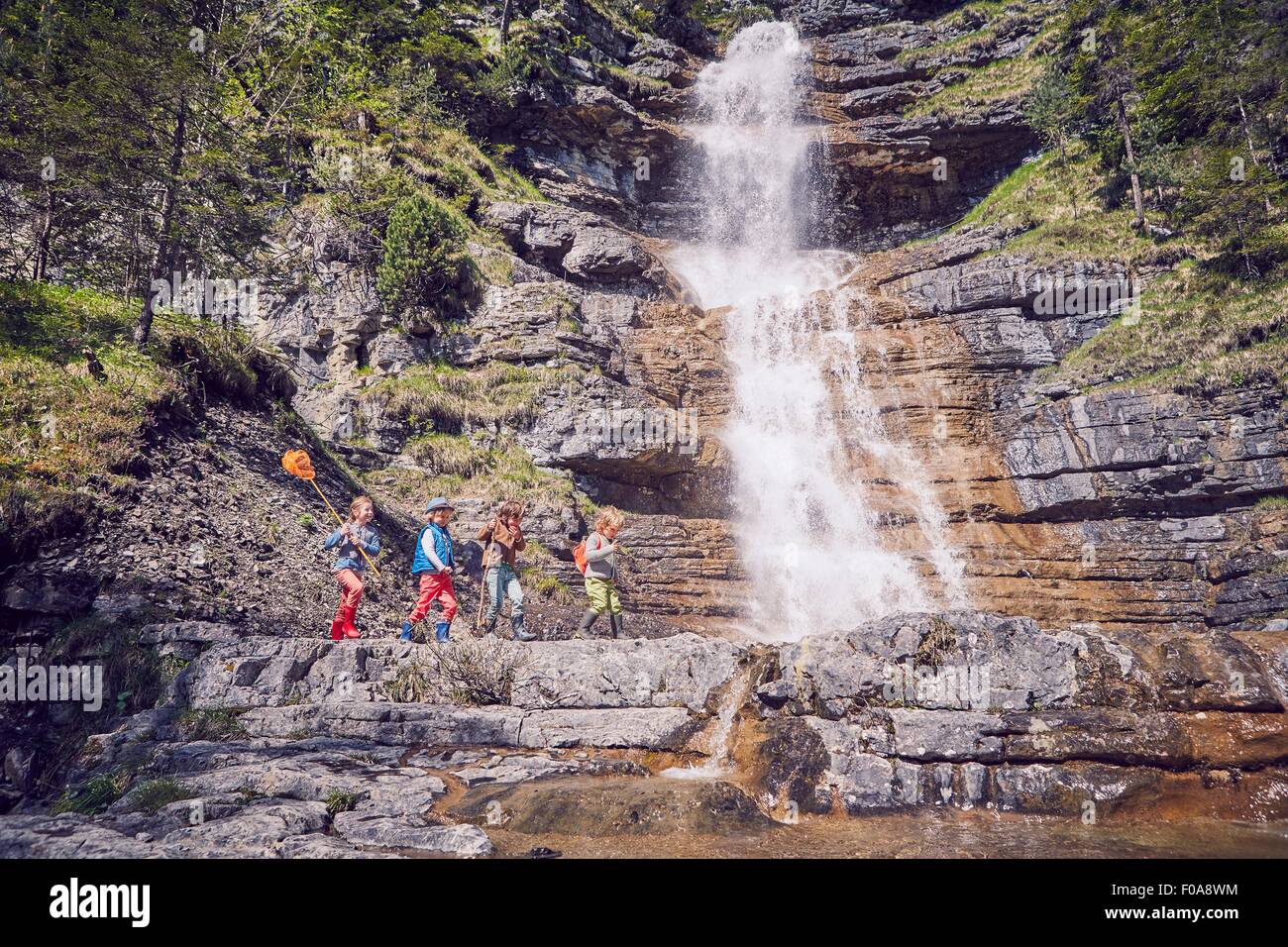 Group of children exploring by waterfall Stock Photo