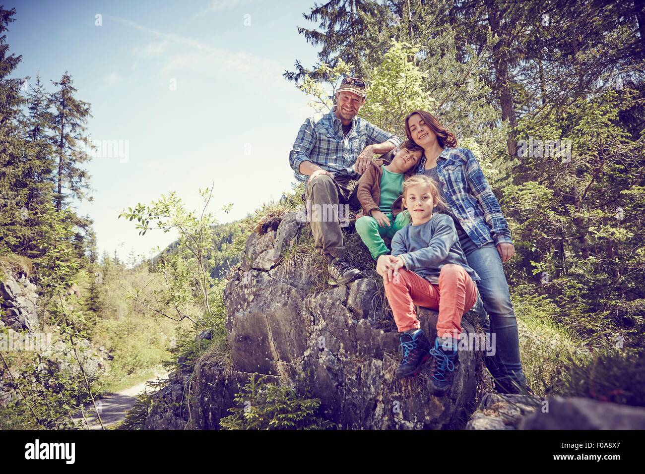Portrait of family sitting on rock in forest Stock Photo