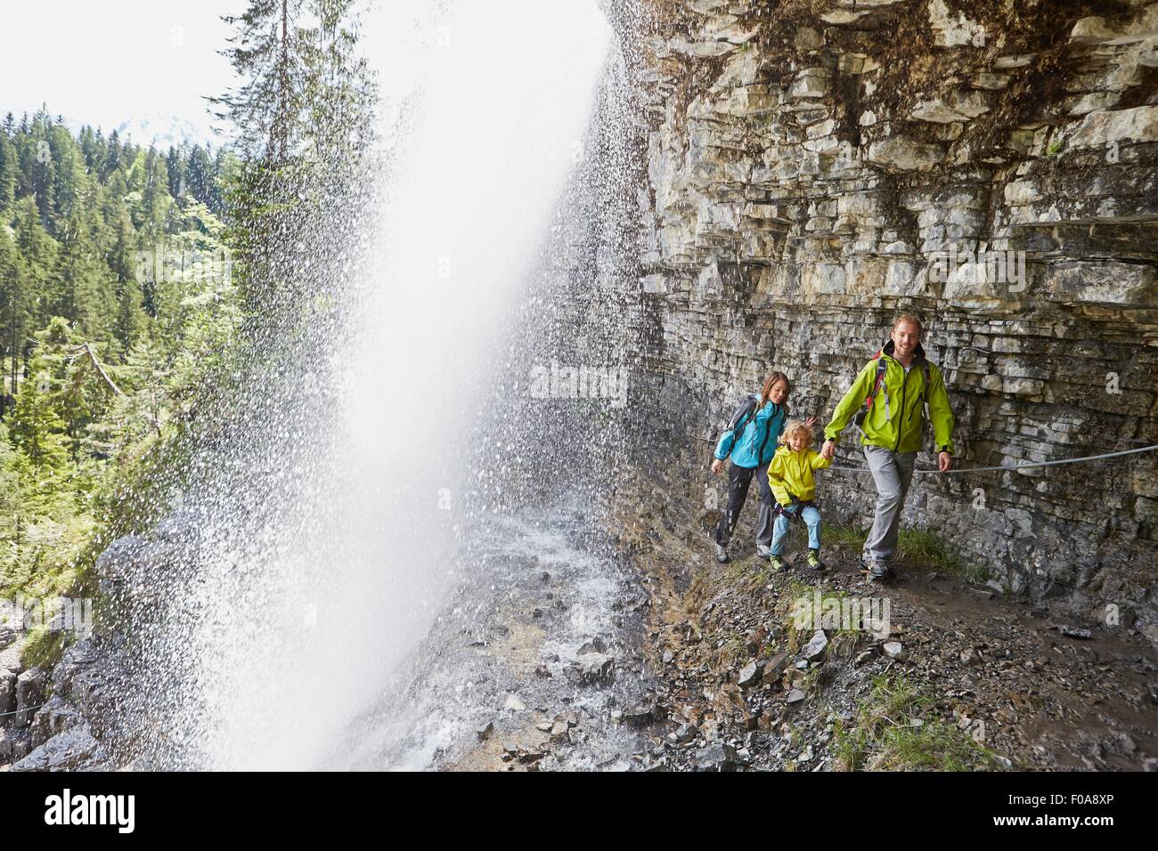 Young family, walking underneath waterfall Stock Photo