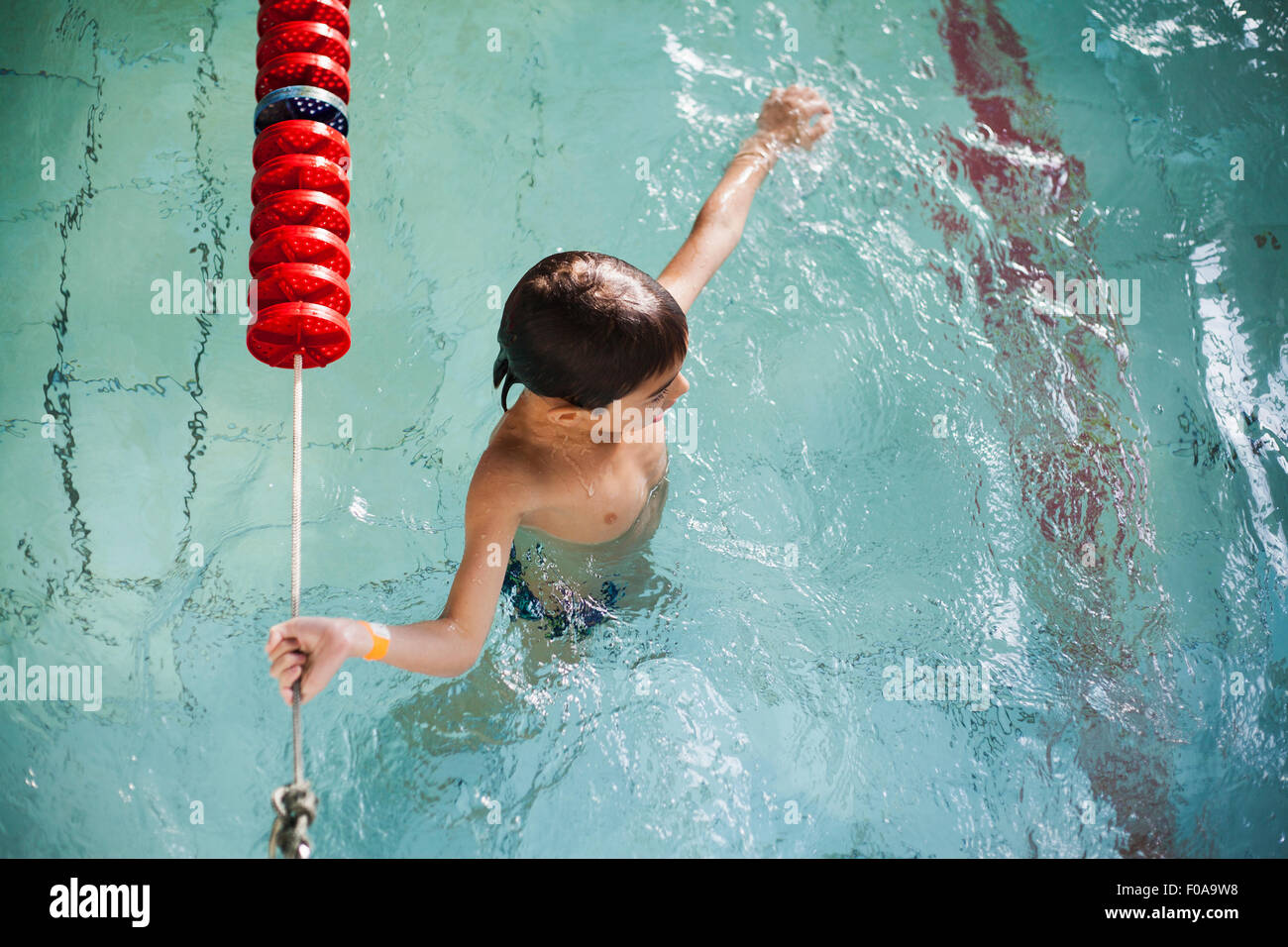 High angle view of boy holding onto rope in swimming pool Stock Photo