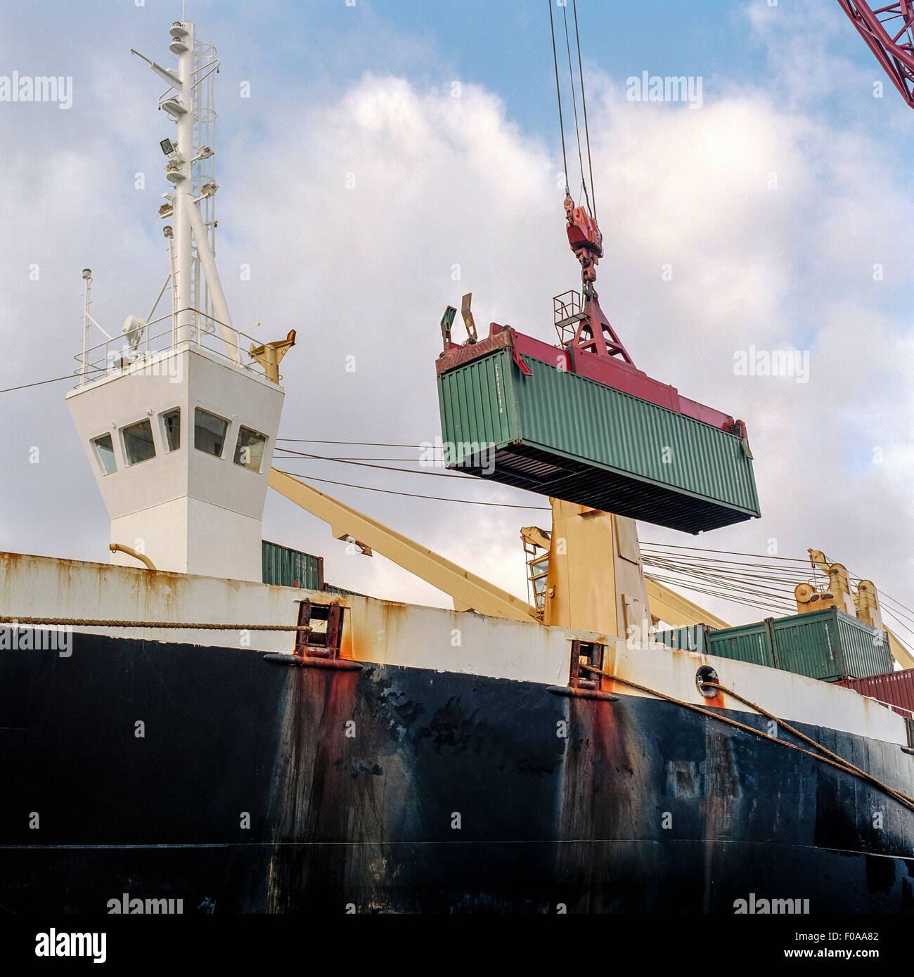 Shipping container being lowered by crane onto ship in port Stock Photo