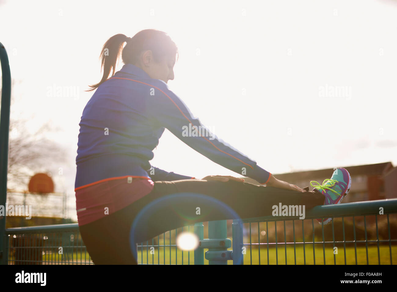 Mature female runner stretching leg on park fence Stock Photo