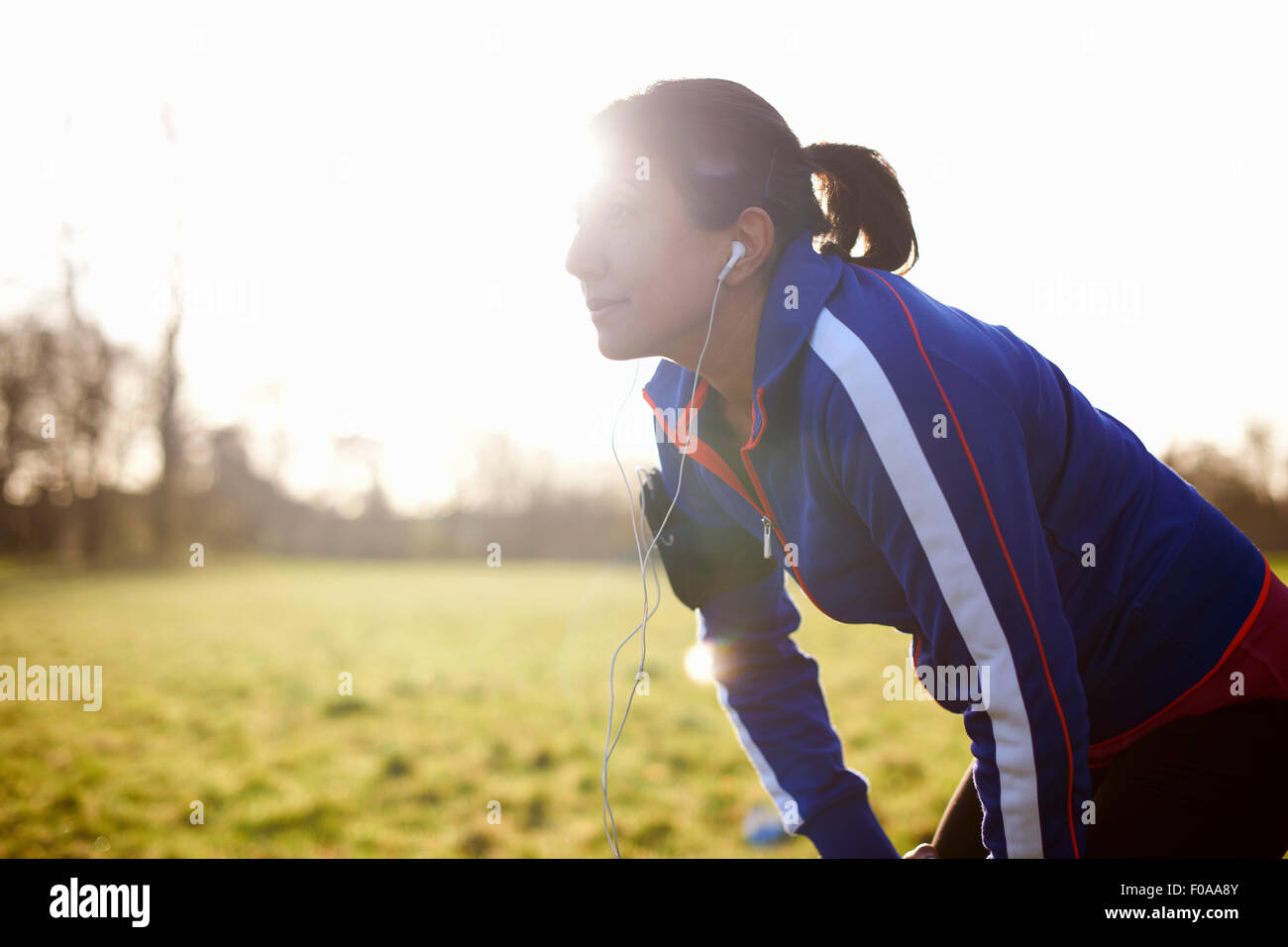 Mature female runner in field taking a break Stock Photo