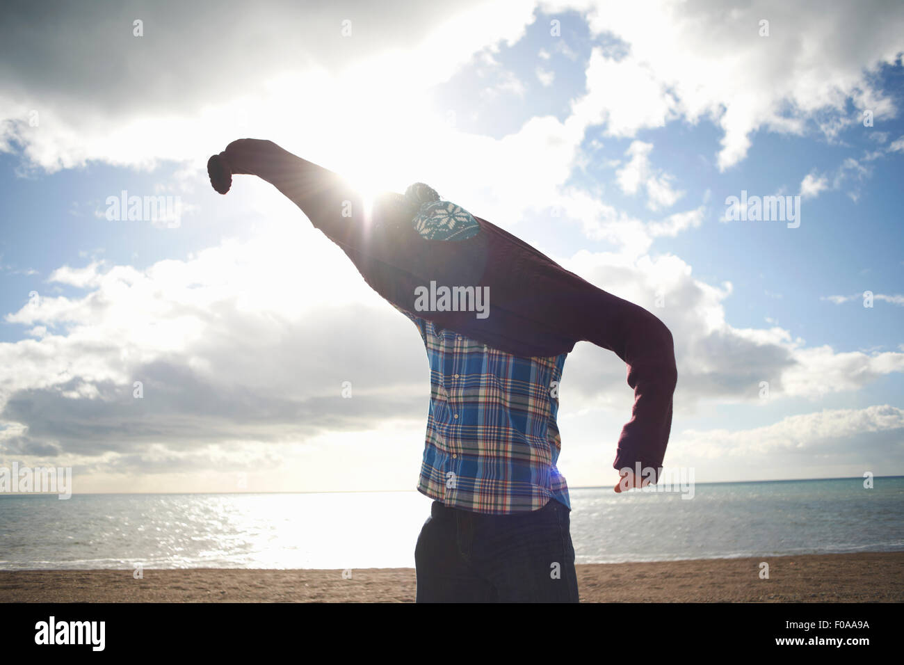 Mature man struggling to put on sweater at beach Stock Photo
