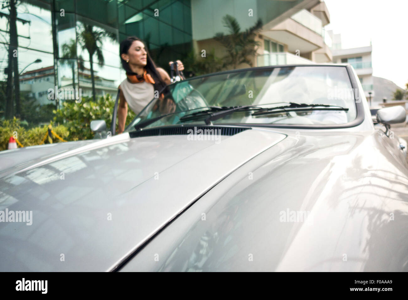 Mid adult woman getting into convertible car Stock Photo