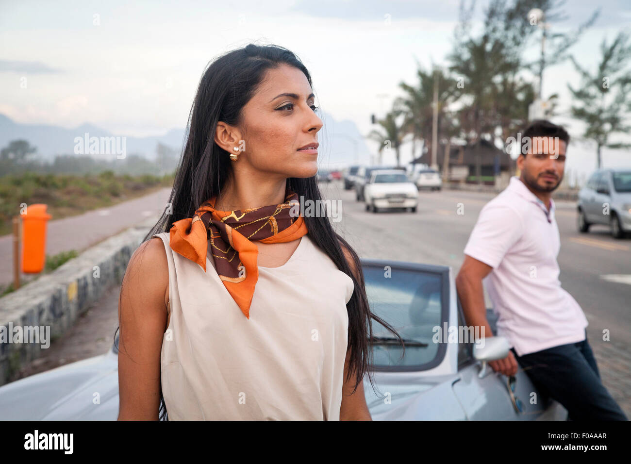 Mid adult couple standing by convertible car by side of road Stock Photo