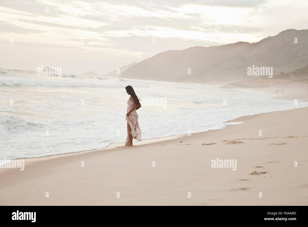 Mid adult woman walking along beach Stock Photo