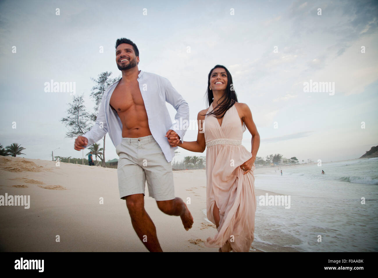 Mid adult couple running along beach, hand in hand, low angle view Stock Photo