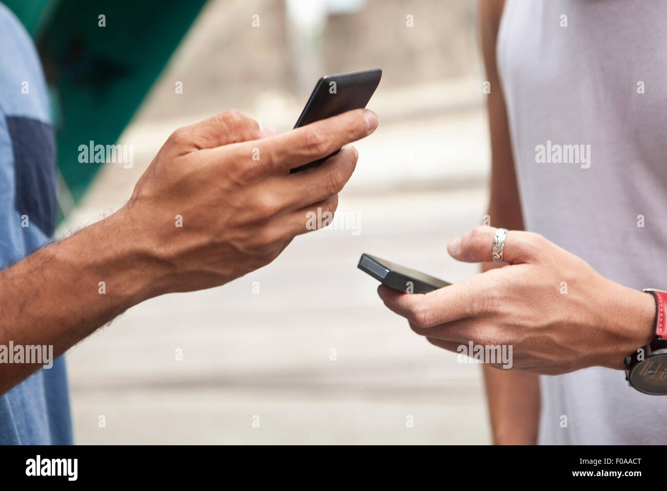 Two men holding smartphones, focus on hands, close-up Stock Photo