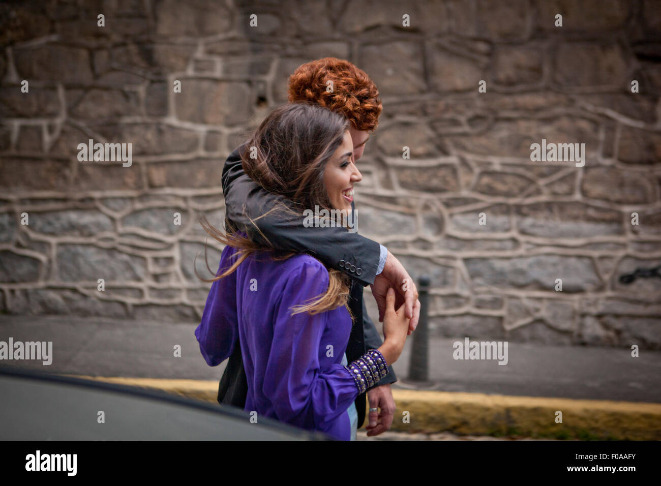 Couple walking along street, arms around each other Stock Photo