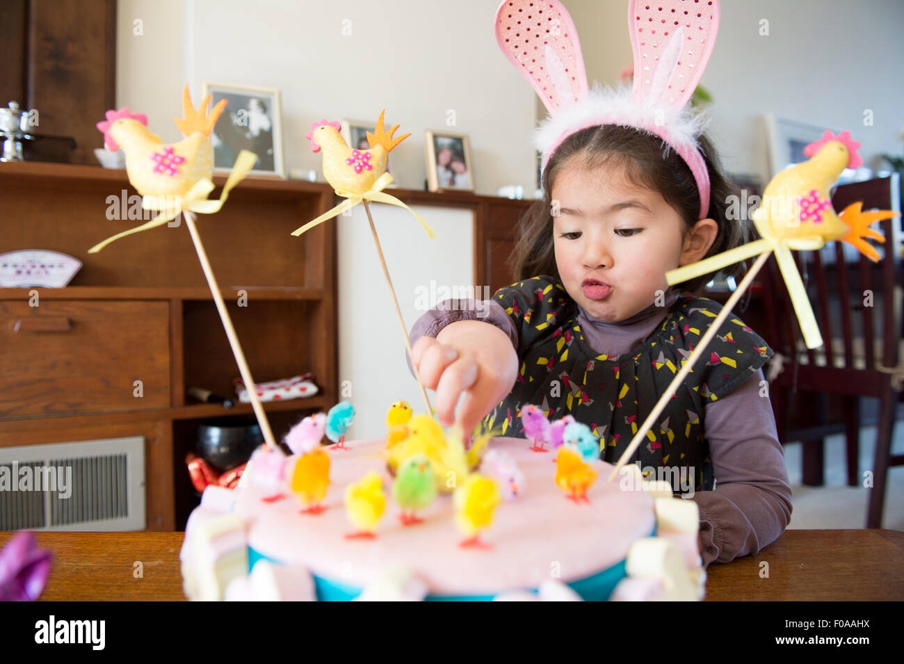 Young girl sitting at table, Easter cake in front of her Stock Photo