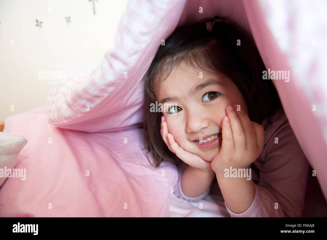 Portrait of young girl, hiding under duvet Stock Photo