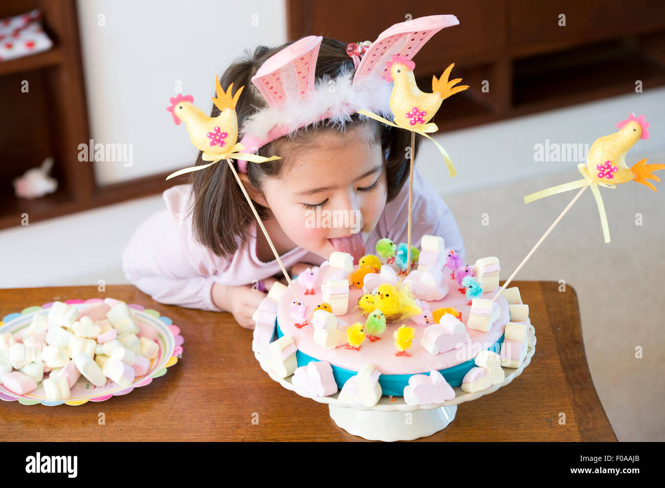 Young girl licking cake on table Stock Photo