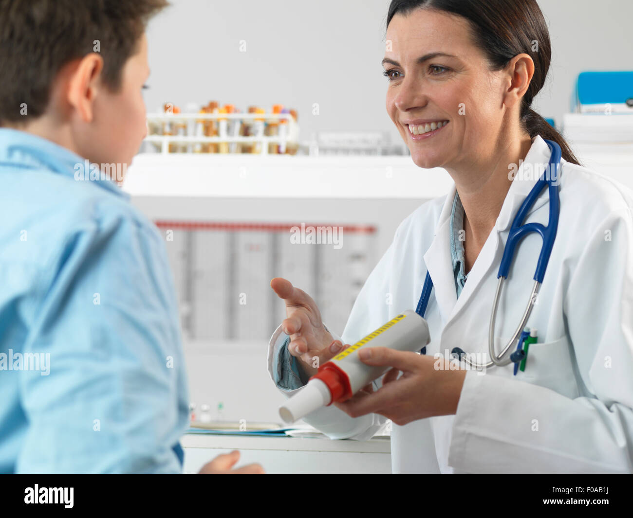 Doctor explaining lung function test to young boy in clinic Stock Photo