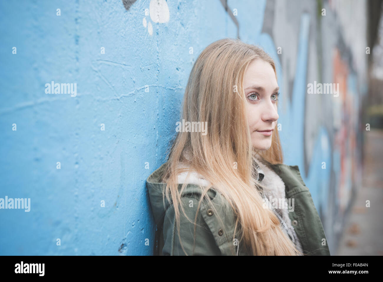 Young woman leaning against graffiti wall Stock Photo