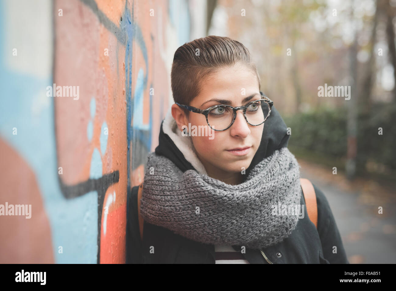 Teenager leaning against graffiti wall Stock Photo