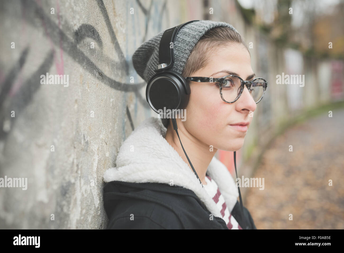 Teenager with headphones by graffiti wall Stock Photo