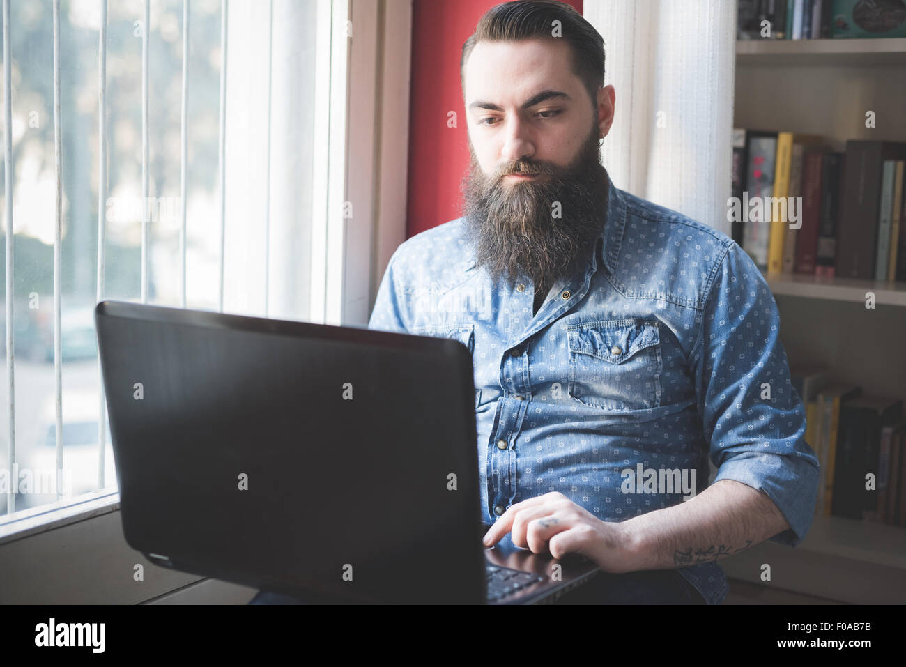Young bearded man using laptop on floor Stock Photo