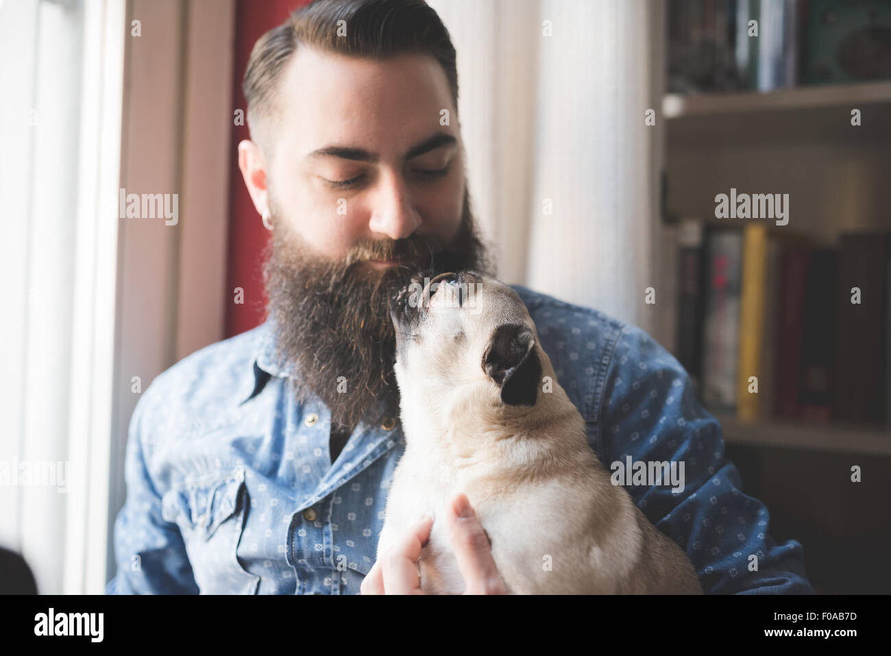 Young bearded man carrying dog in arms Stock Photo