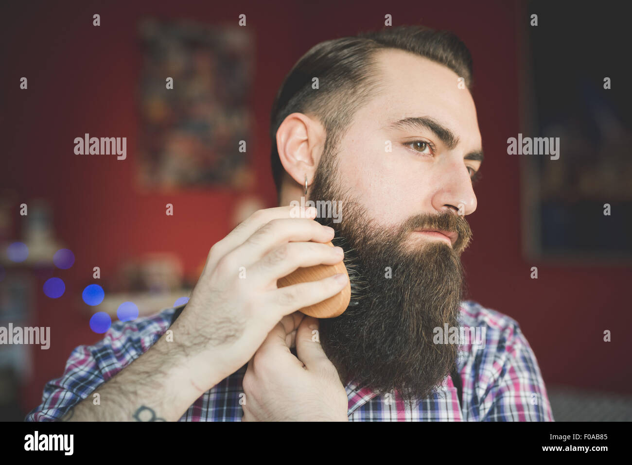 Young bearded man brushing his beard Stock Photo