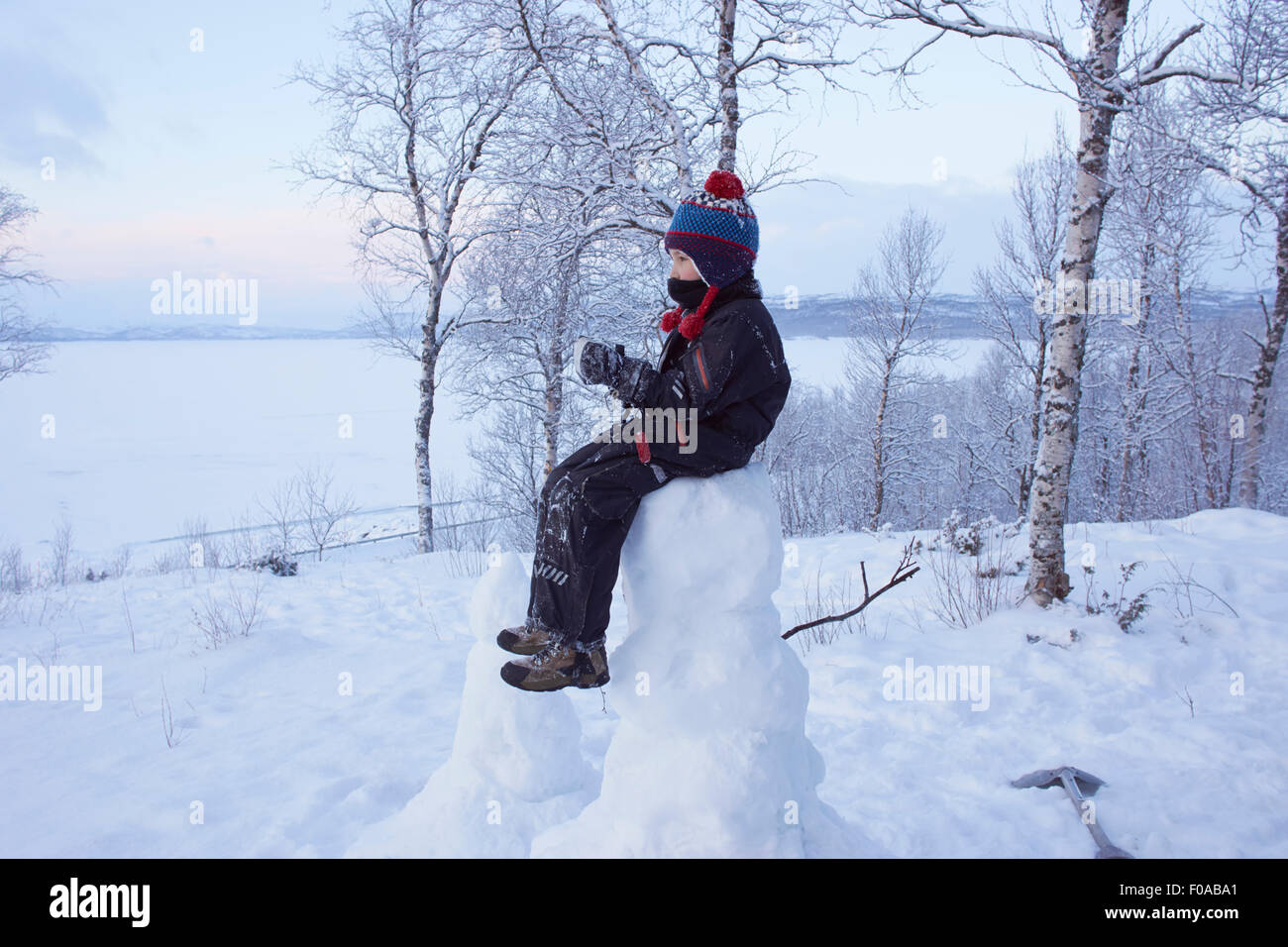 Boy sitting on top of snow man, Hemavan,Sweden Stock Photo