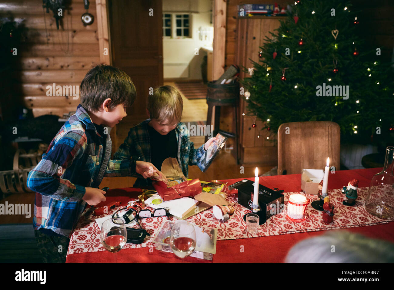Two brothers opening Christmas presents at table Stock Photo