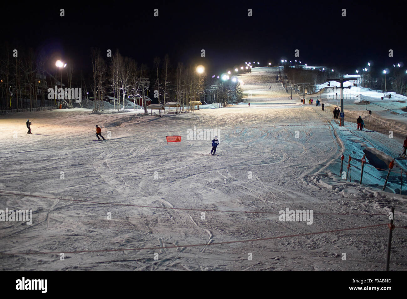 Skiers skiing down ski slope at night, Hemavan, Sweden Stock Photo