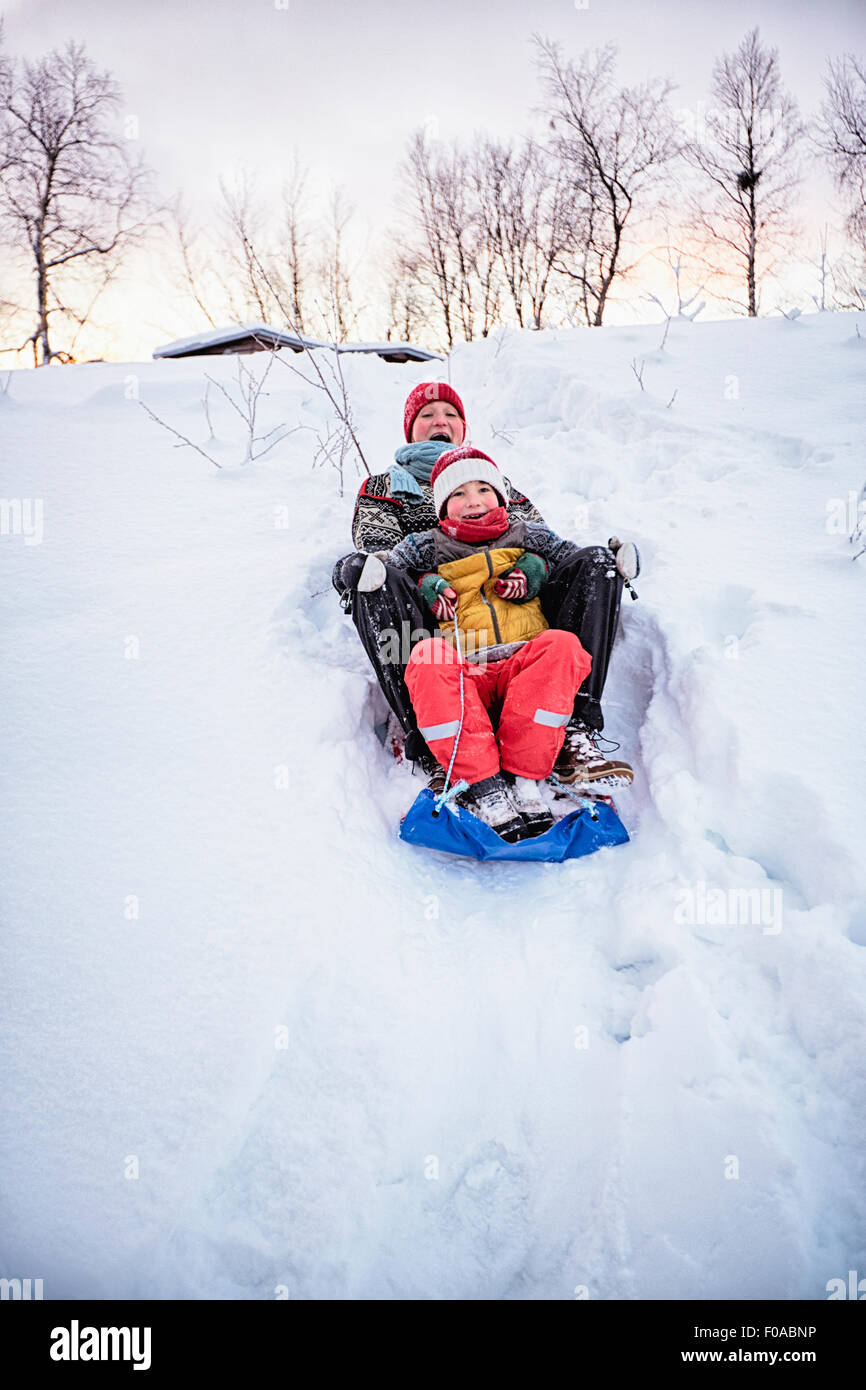 Two brothers playing on toboggan on snow covered hill, Hemavan,Sweden