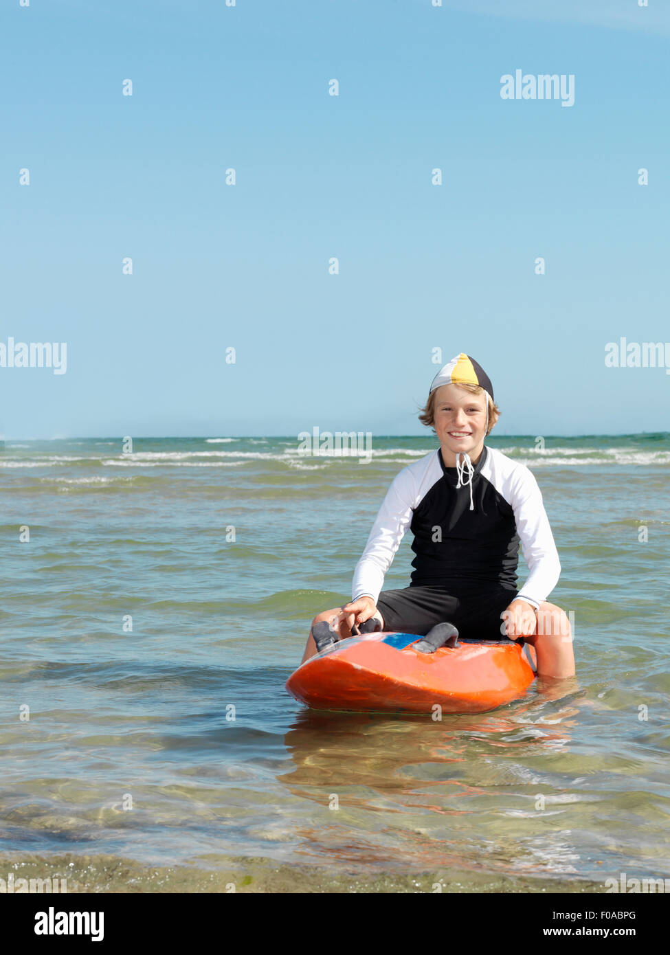 Portrait of boy nipper (child surf life savers) astride surfboard