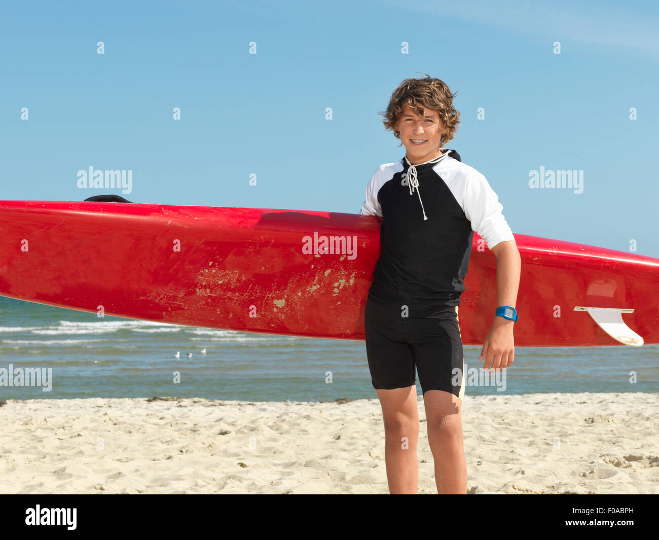 Portrait of teenage boy nipper (child surf life savers) with surfboard